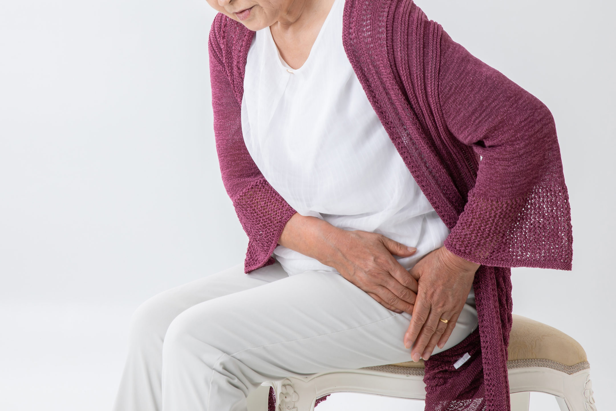 A sitting woman holds her hip in pain. 