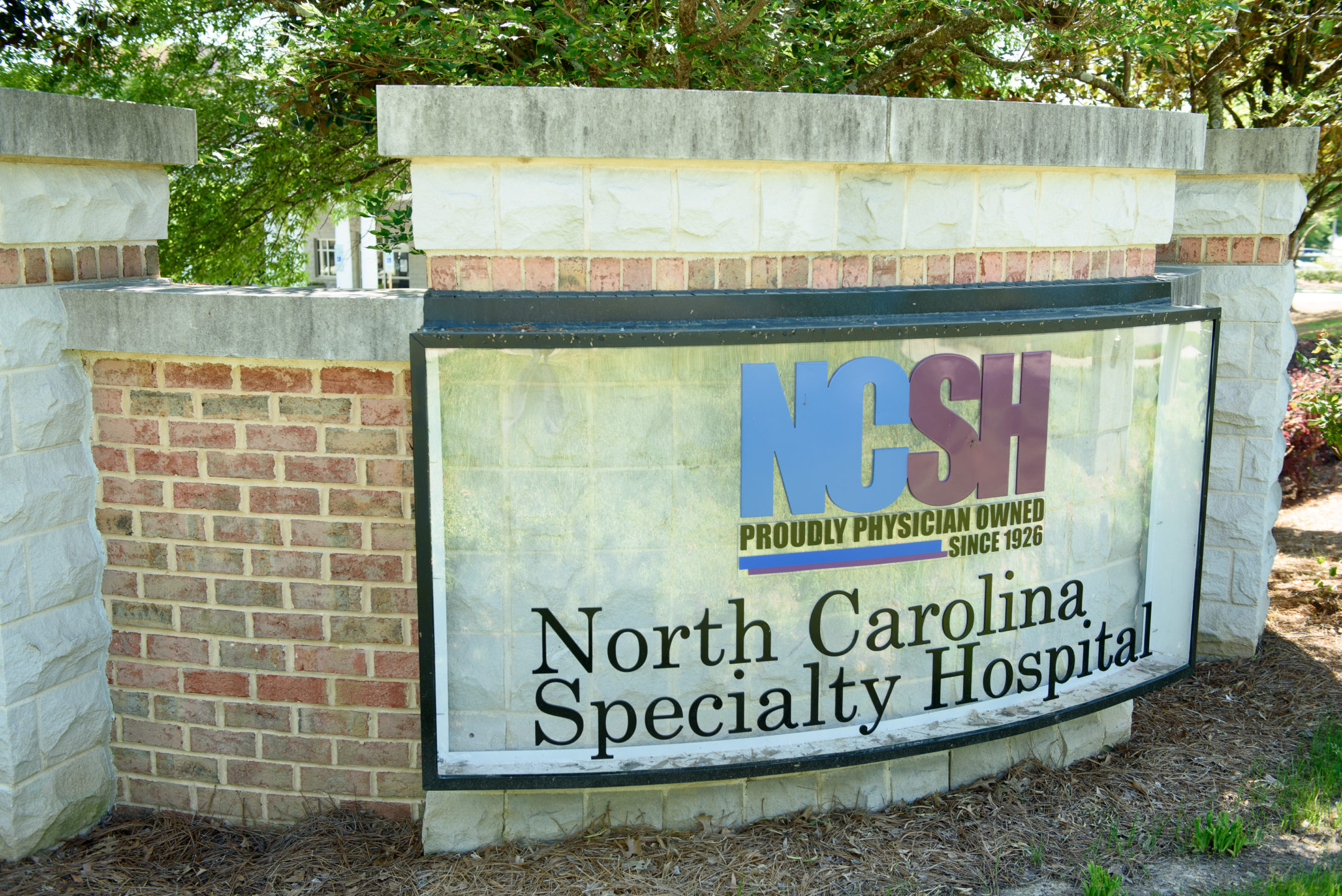Close up of North Carolina Specialty Hospital sign on brick wall by hospital where people go for breast reduction surgery. 