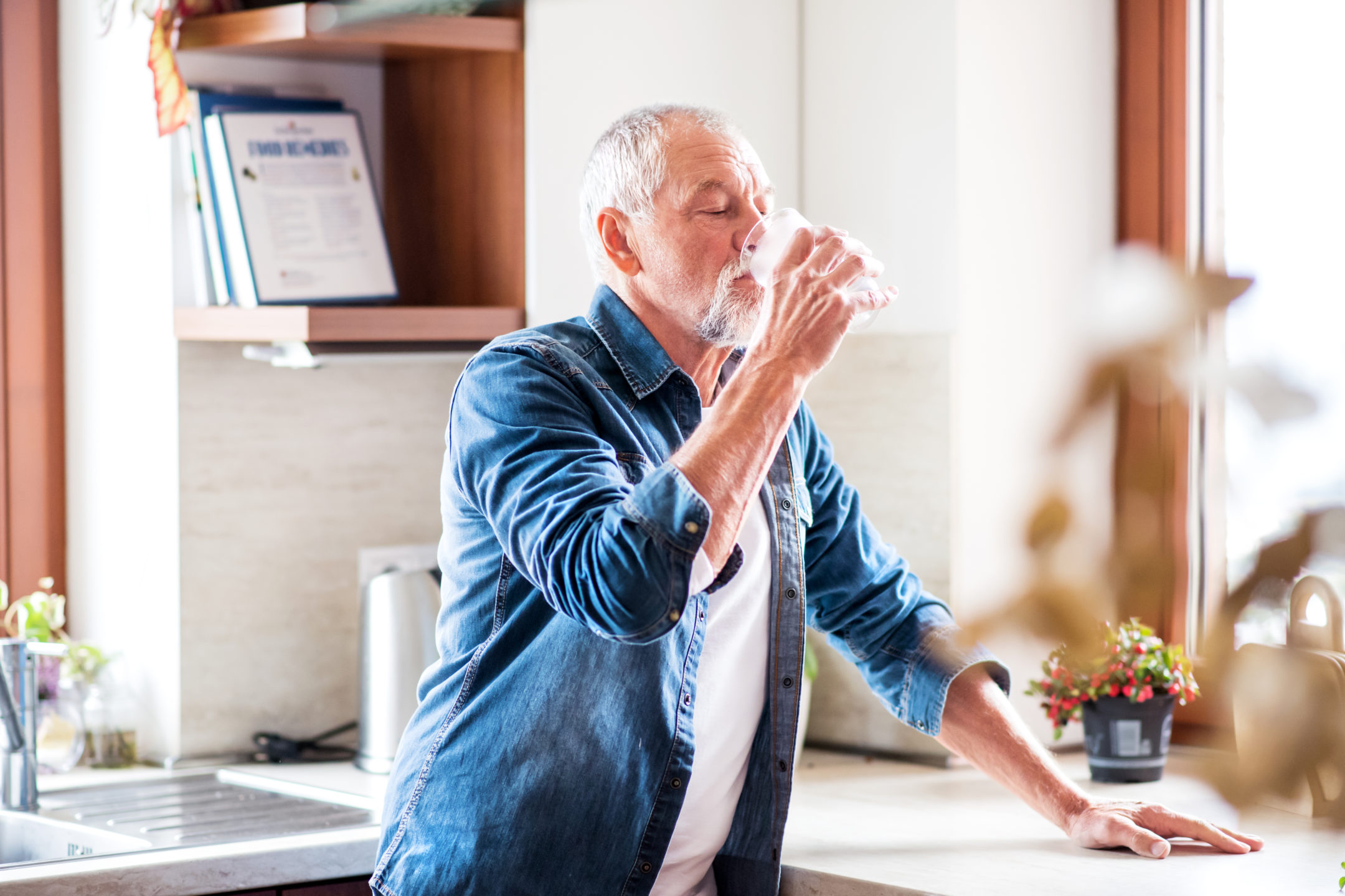 Senior man drinks water at home. 