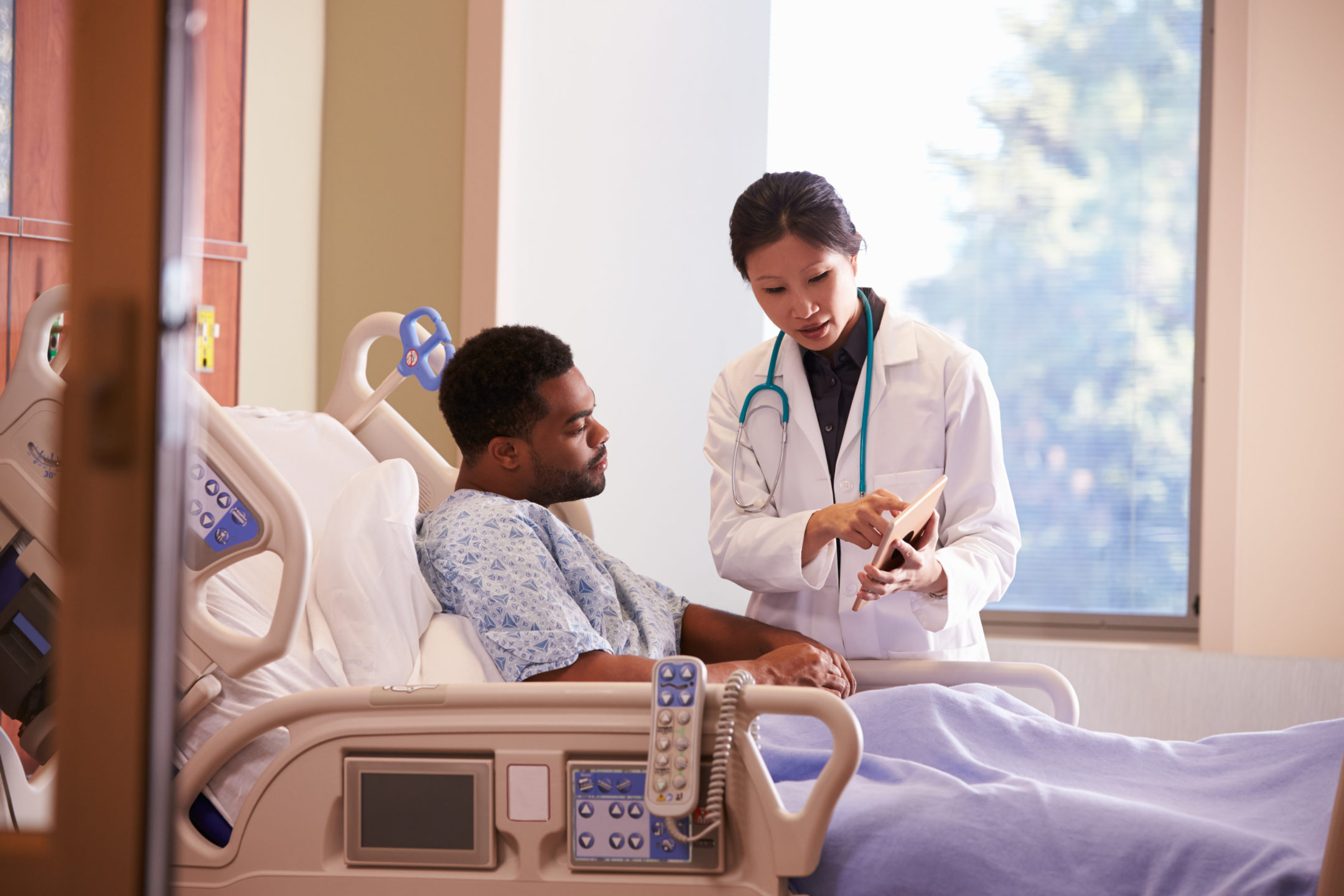 A physician talks to a patient in a hospital bed. 