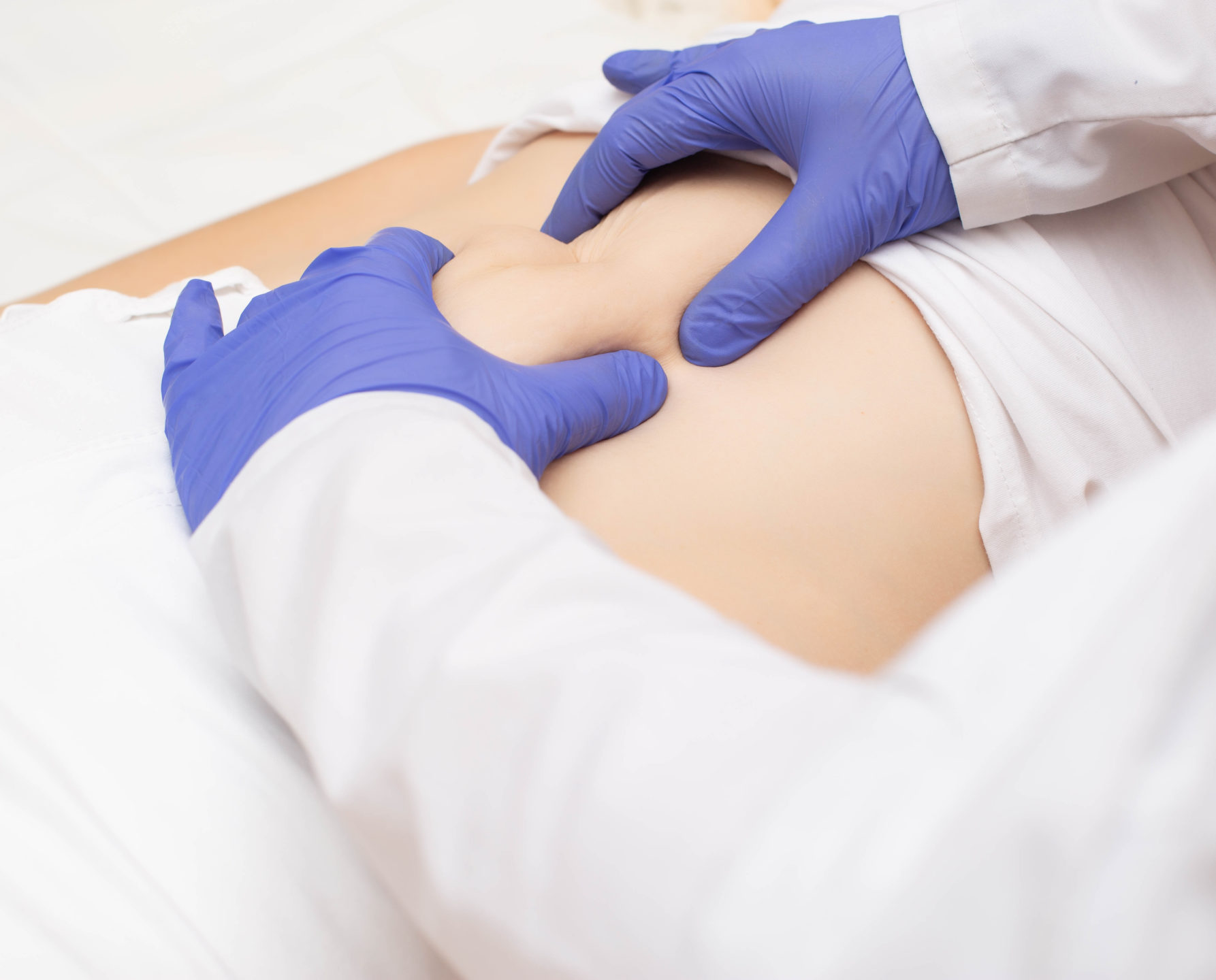  A doctor with gloves on examines a patient’s abdomen.