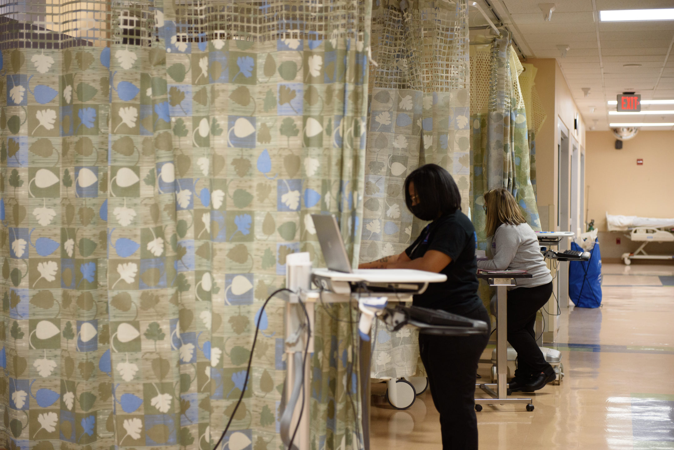 Staff work with patients behind curtained areas. 