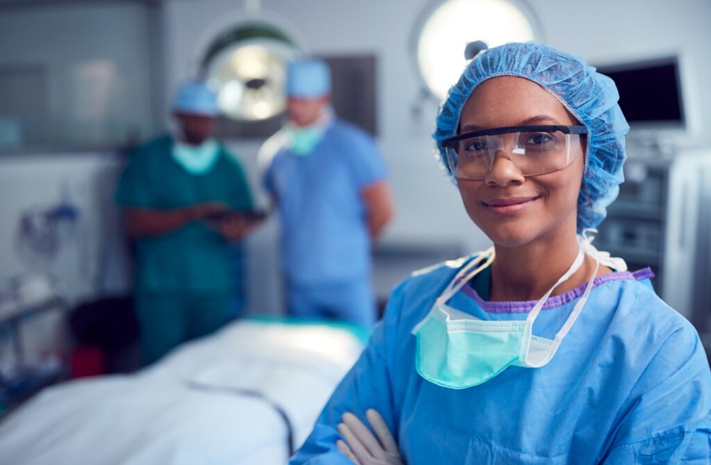A female plastic surgeon waits in an operating room for her nonbinary top surgery patient. 