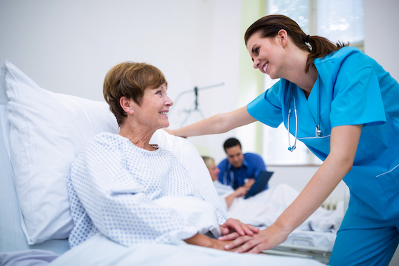 A nurse speaks to a patient in a hospital bed after general surgery.