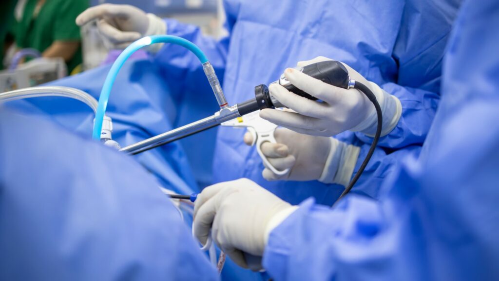 Close-up of orthopedic surgeons’ hands in gloves and holding instruments as they operate on a patient’s MCL tear.