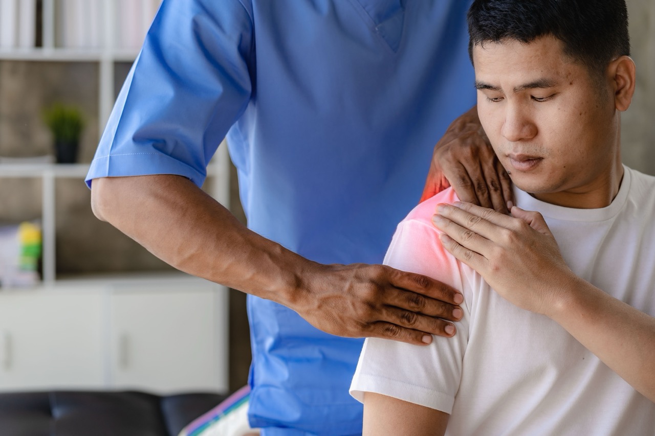 A doctor puts his hands around the shoulder of a man suffering from a rotator cuff tear.