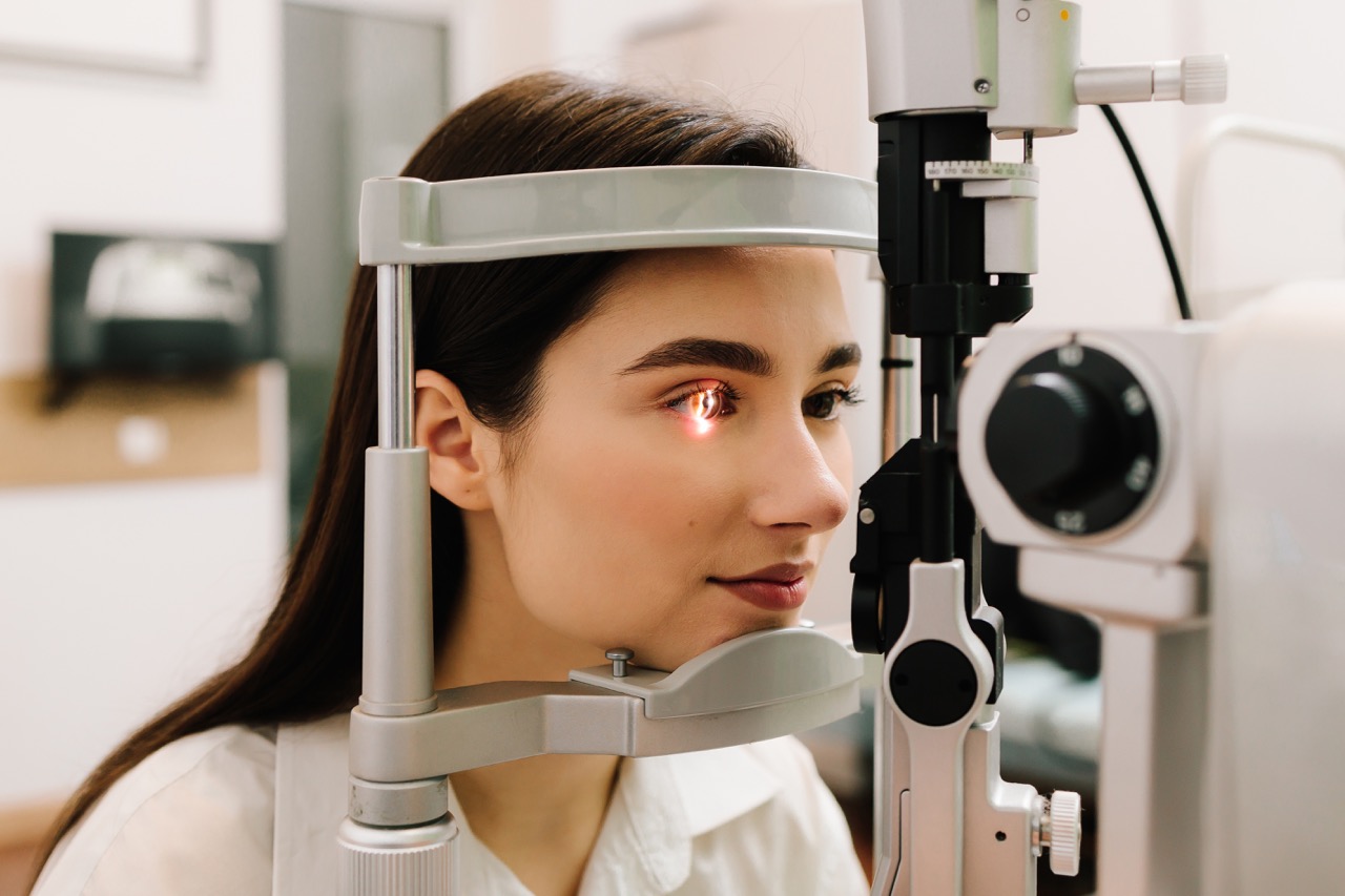 A photo of a woman’s face undergoing a retinal eye exam with the light shining in one of her eyes.